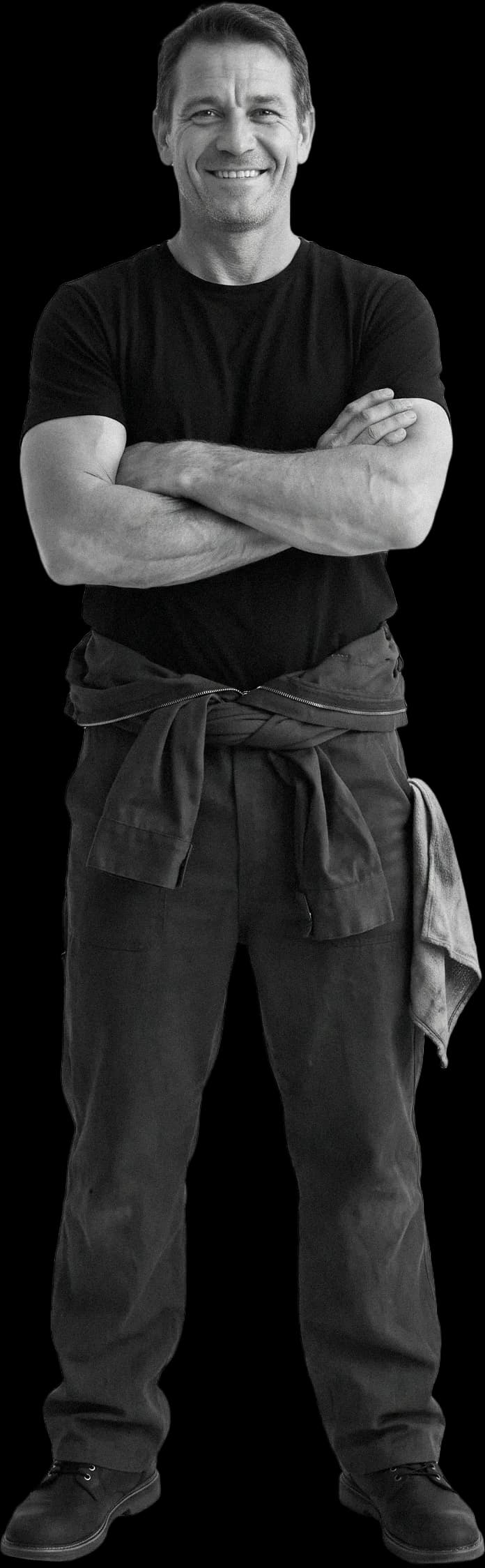 A car mechanic in overalls, arms crossed, smiling